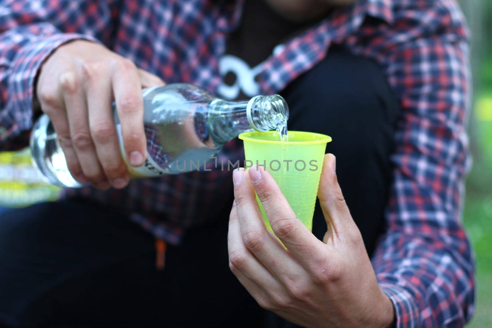 guy pouring alcohol into a plastic cup , sport