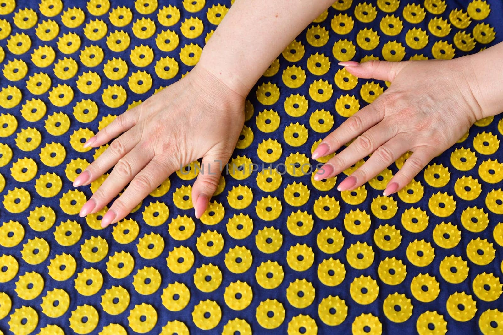 Women's arm on needle mat - massage using an applicator Kuznetsov, Russia
