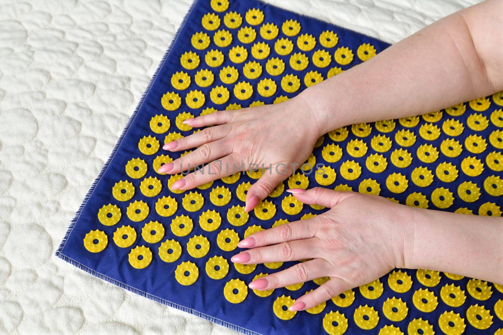 Women's arm on needle mat - massage using an applicator Kuznetsov, Russia