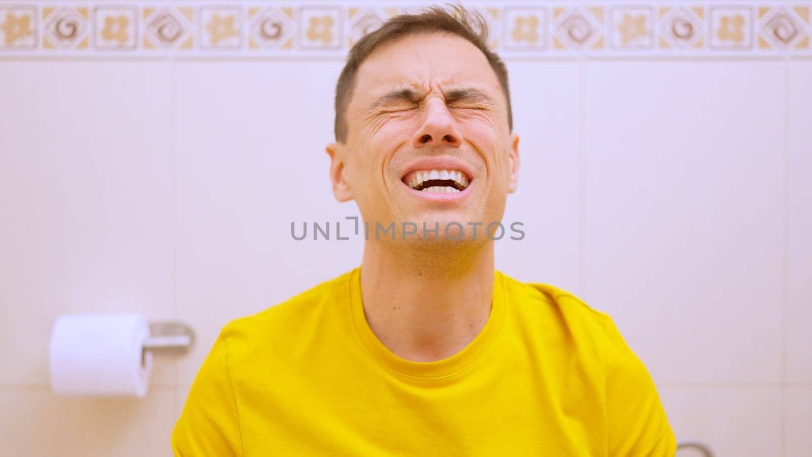 Man sitting on toilet and making an effort because of constipation