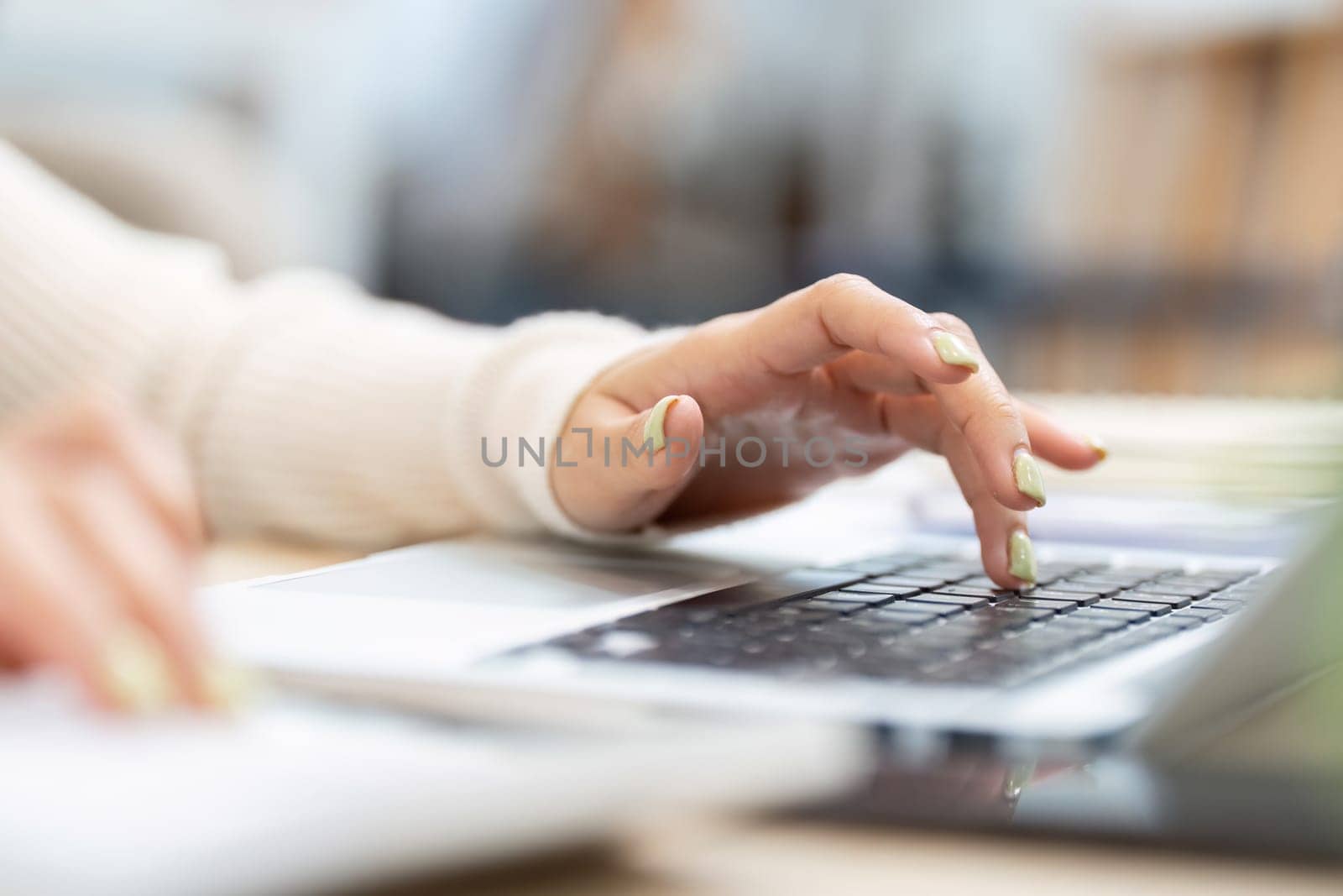 A woman focuses on her laptop, typing and working on important tasks in a contemporary workspace.