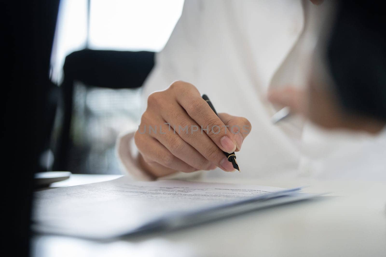 A close-up view of a hand signing financial documents, highlighting the importance of accuracy in tax preparation.