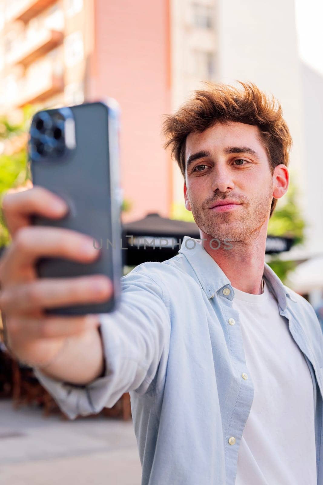young man taking a selfie with cell phone, he is happy and enjoying the moment, concept of technology of communication and urban lifestyle
