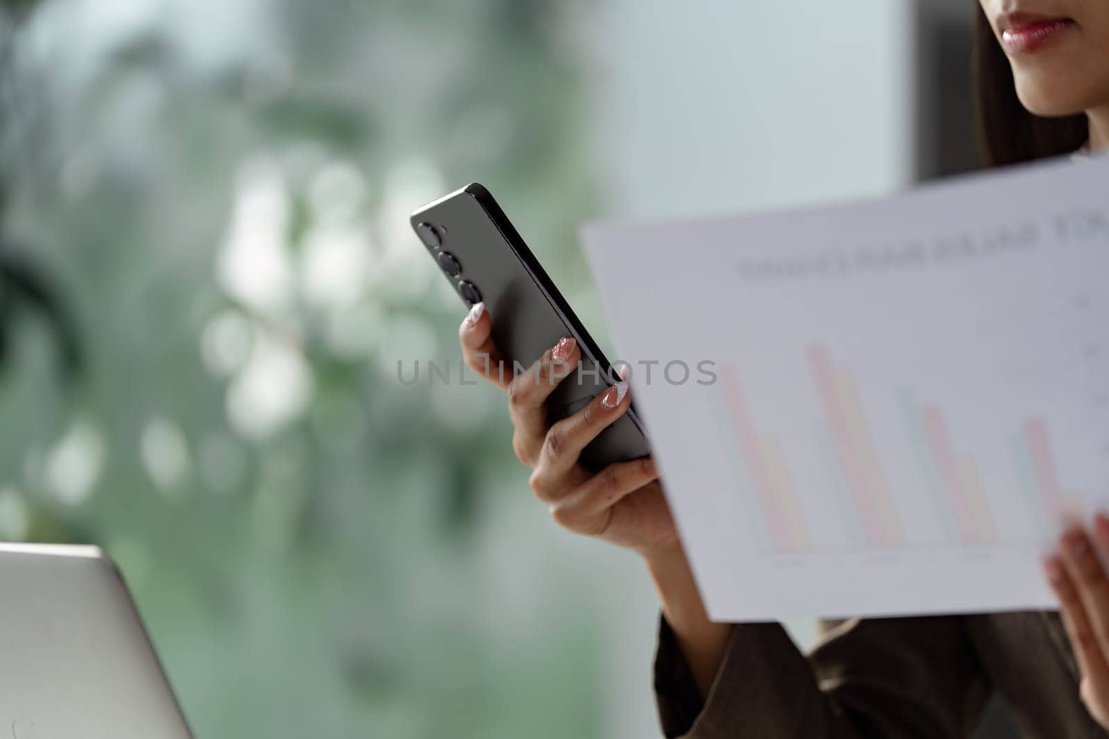 A business professional engages in a phone call, reviewing financial documents and charts, emphasizing communication and analysis.