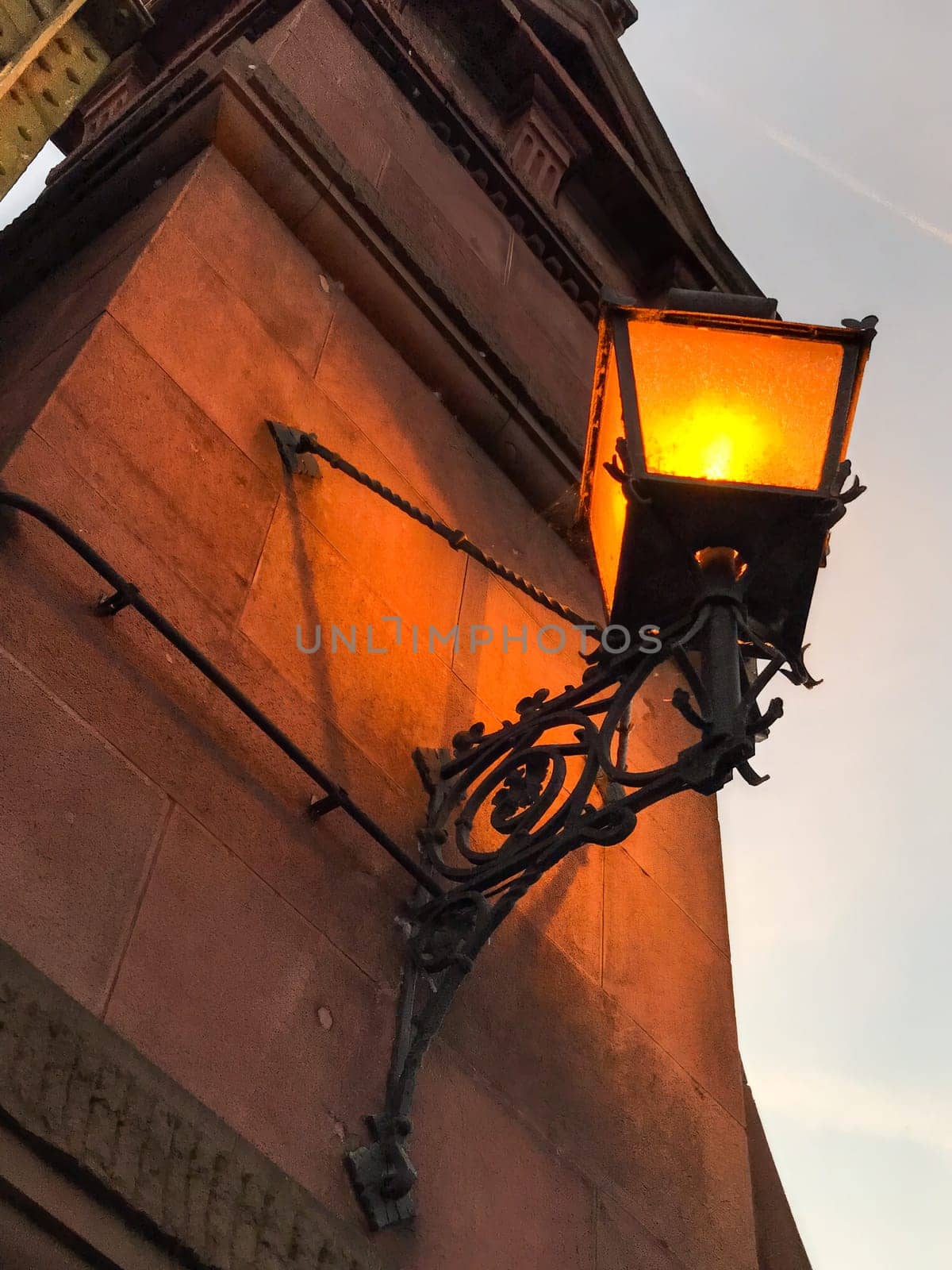 An old lantern glows on the wall at dusk. High quality photo