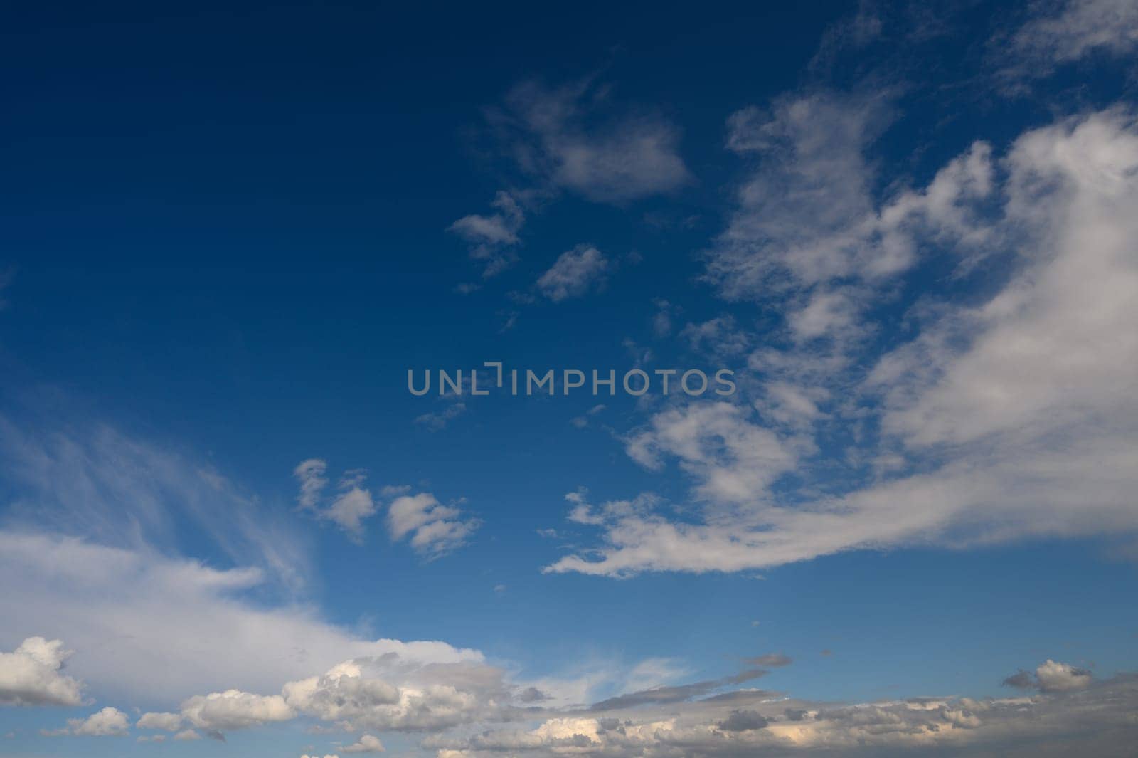 Expansive blue sky dotted with soft, white clouds creates a serene atmosphere in the afternoon light.