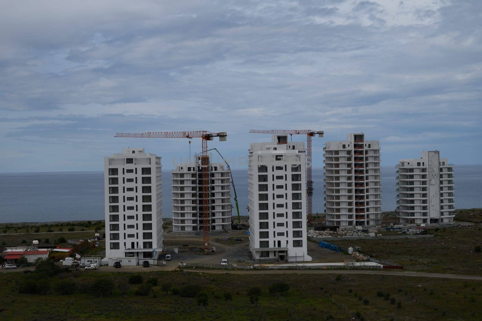 New residential towers rise against a dramatic sky, showcasing progress near the ocean's edge in a coastal community.