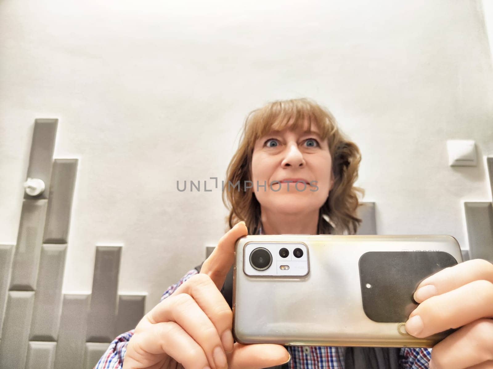 Blonde woman captures a cheerful selfie in the mirror, showcasing her morning look in a stylish bathroom.