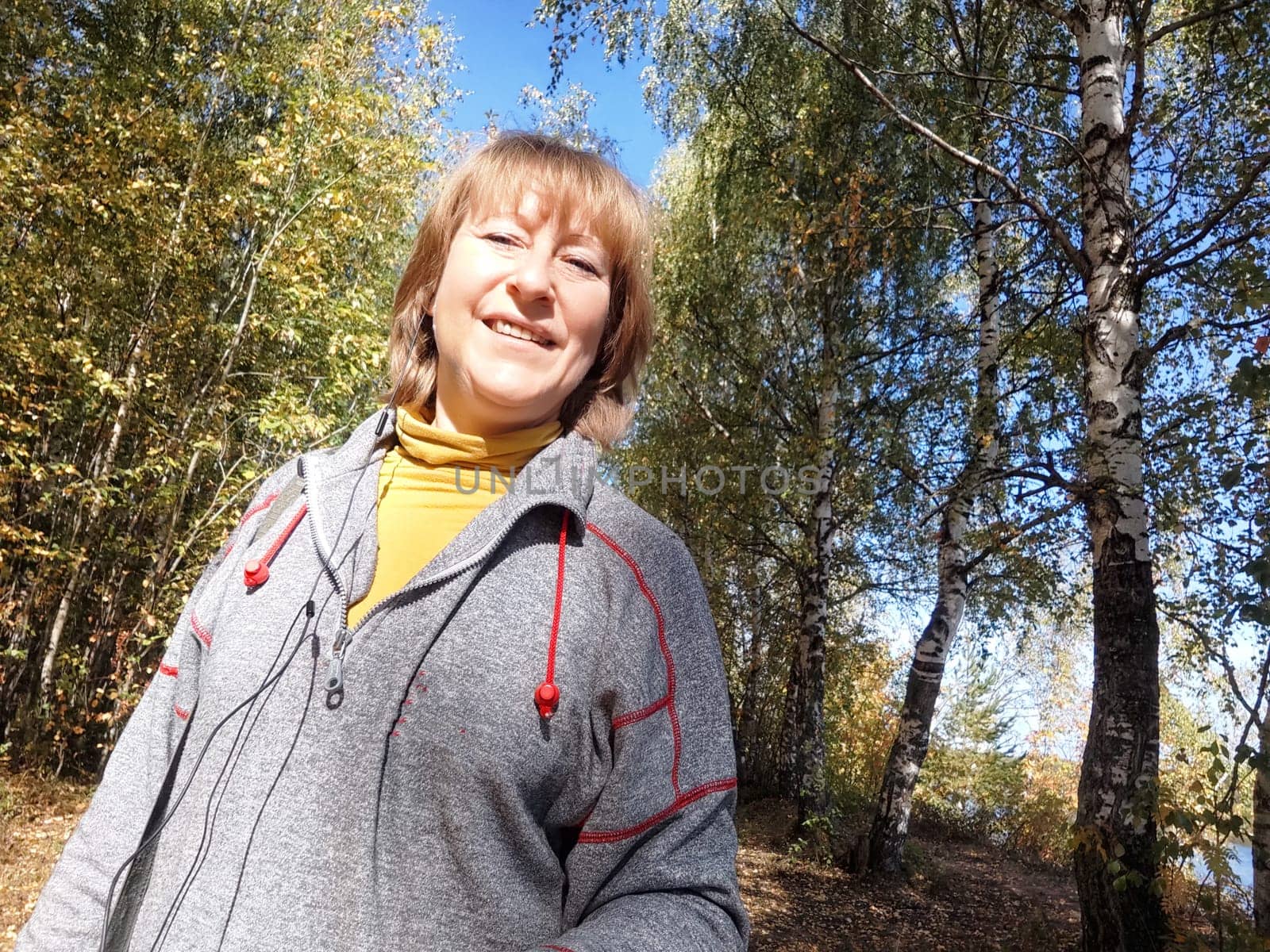 Blonde woman captures a joyful moment on an autumn nature trip amid colorful trees and serene surroundings