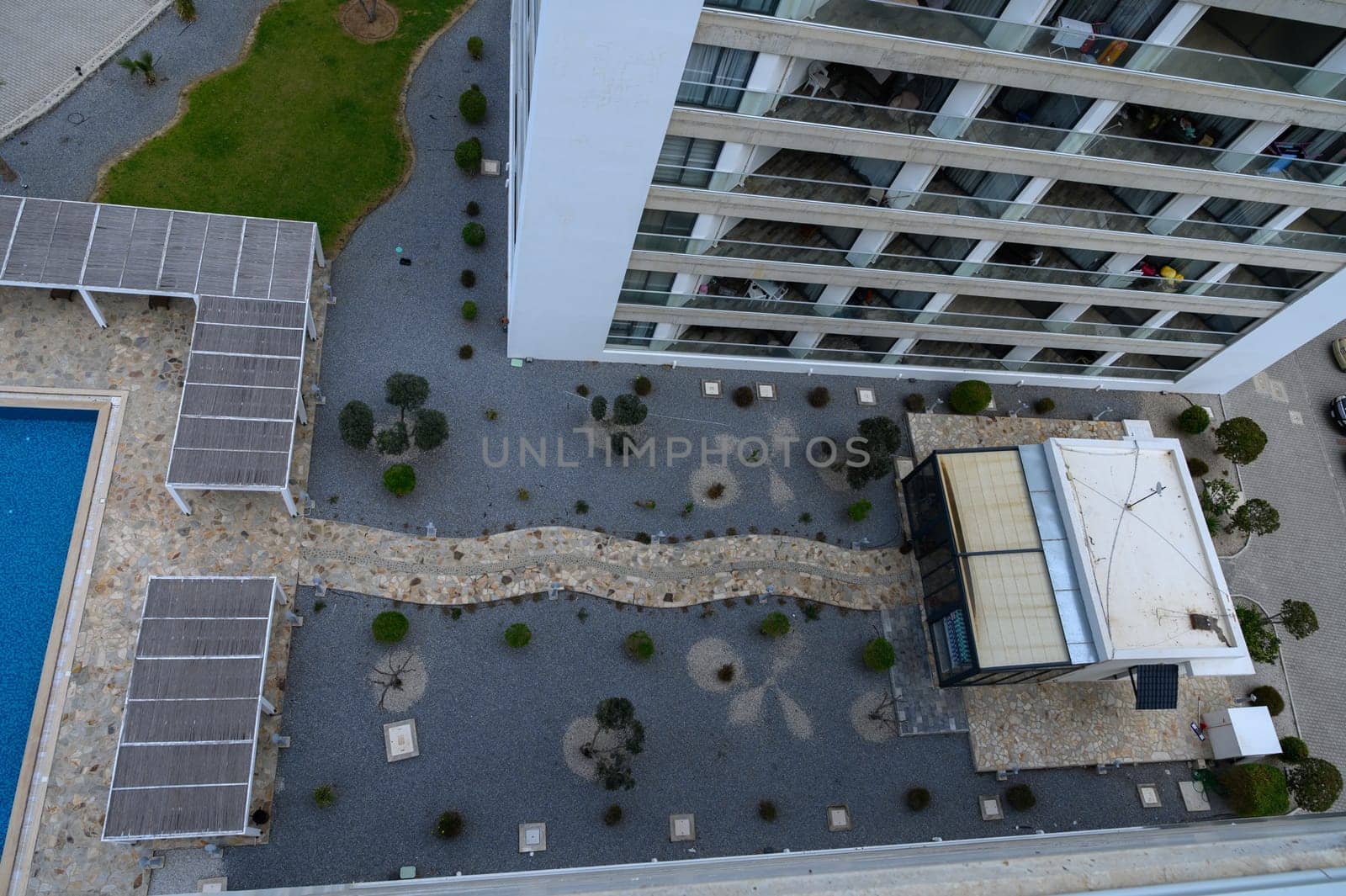 A peaceful courtyard reveals winding pathways, plants, and a striking modern architecture under clear skies.