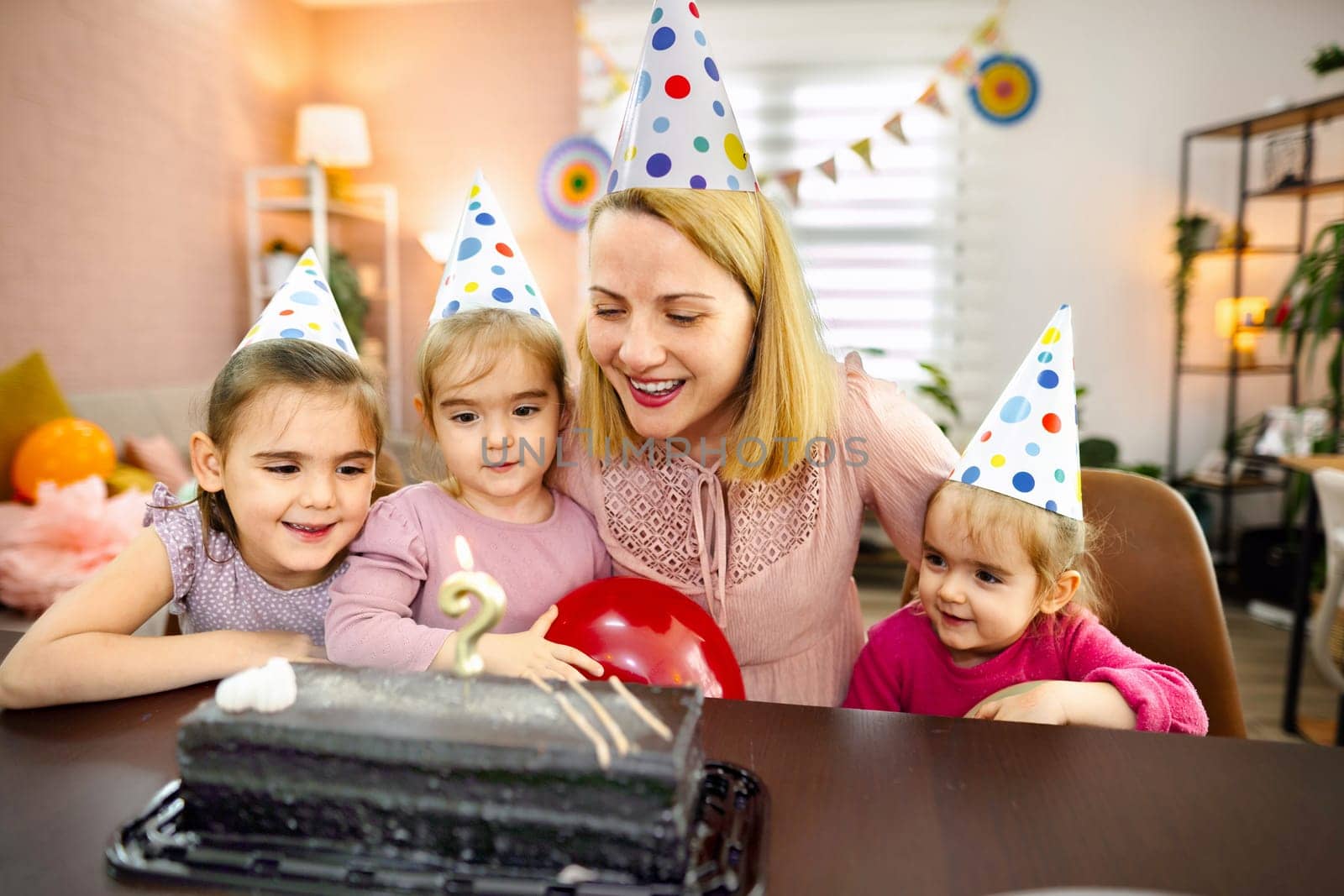Happy family gathering features children excited about cake and candles.