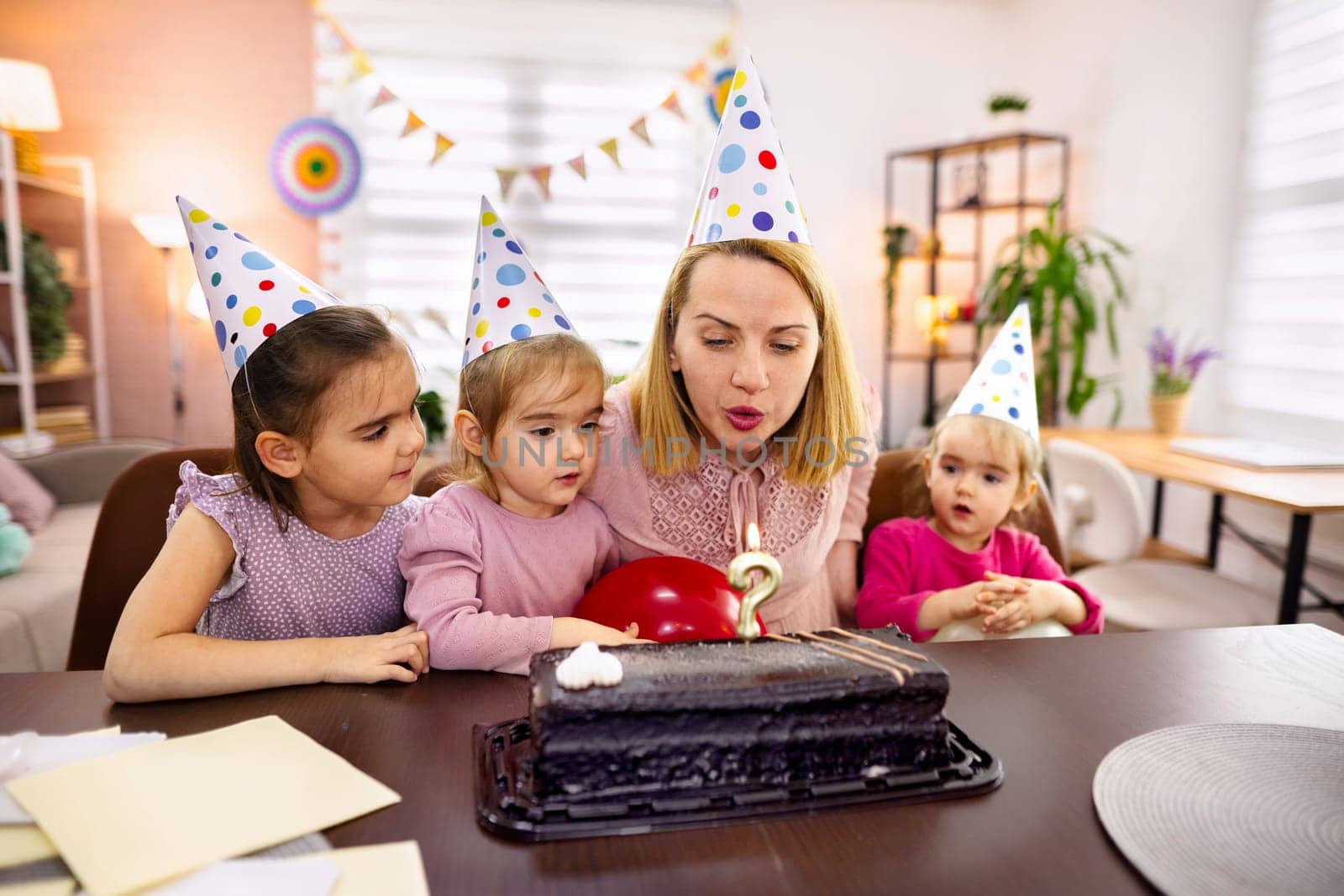 Children sing joyfully at a festive birthday cake celebration.