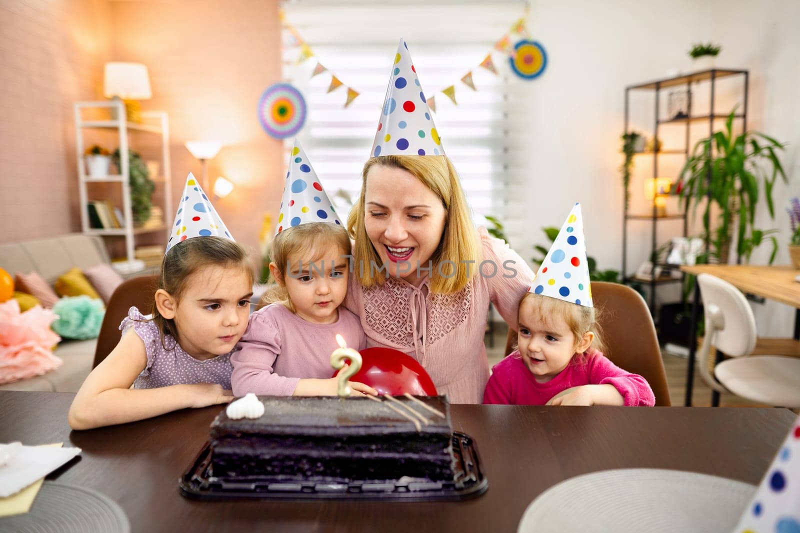 Children gather around a cake, excited for the birthday celebration.
