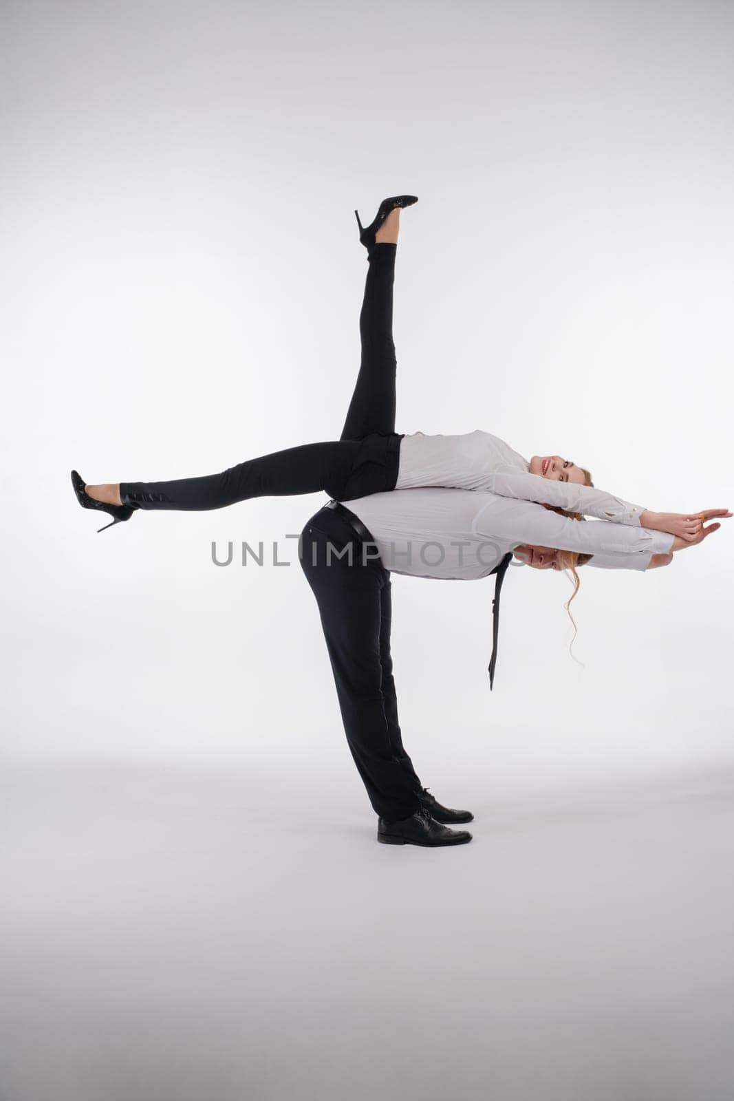 A couple showcases their athletic skills with a dynamic acrobatic pose in a professional setting, highlighting teamwork.