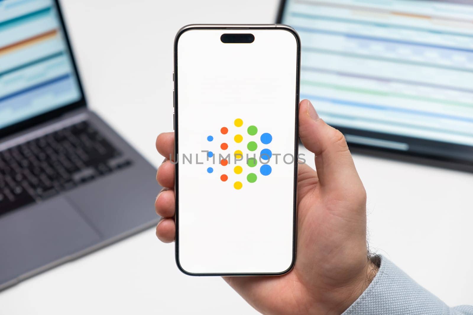 PRAGUE, CZECHIA - JULY, 2024: Google AI logo on the screen of smartphone in mans hand and laptop on the background