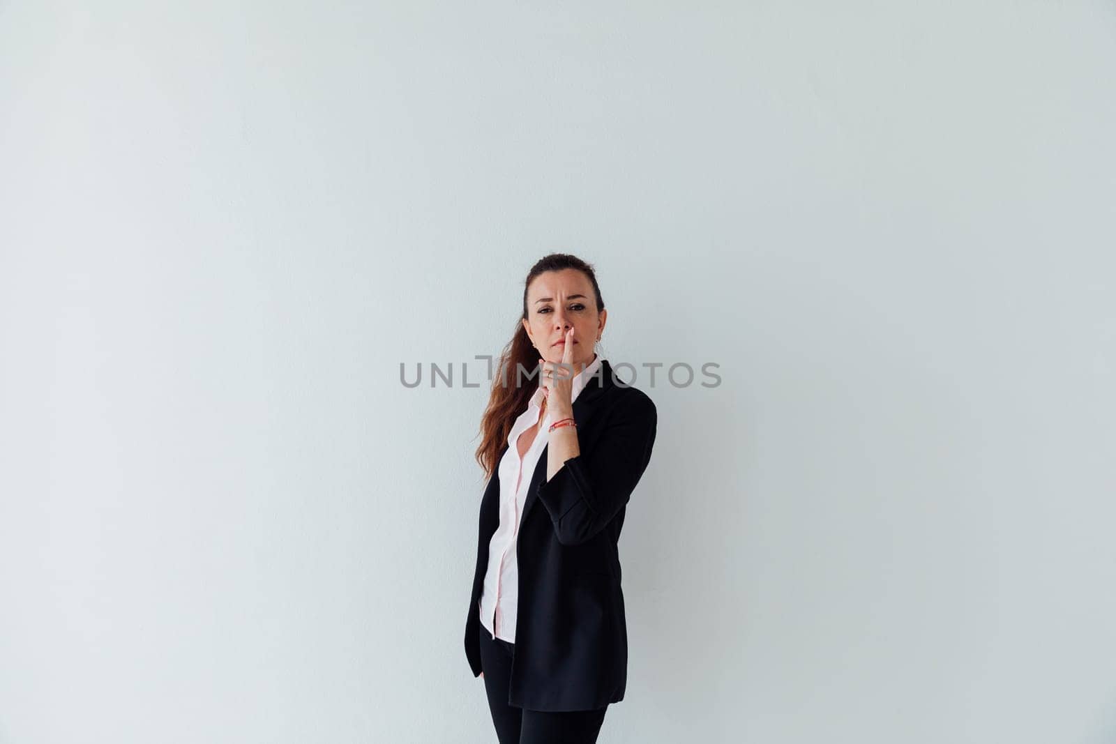Portrait of a beautiful woman of 40 years old in a business suit near a white wall