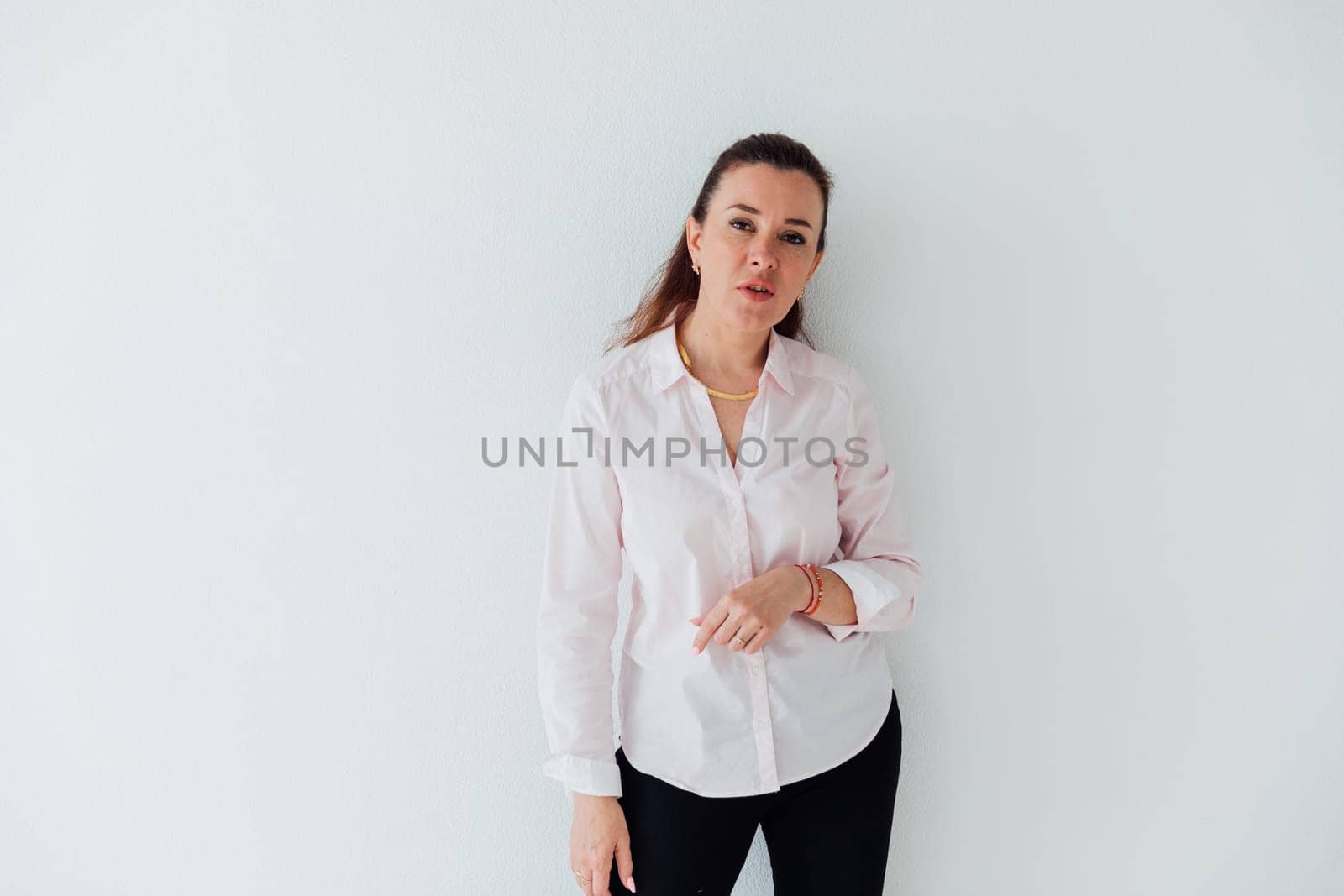 Portrait of a woman of 40 years old in a business suit near a white wall