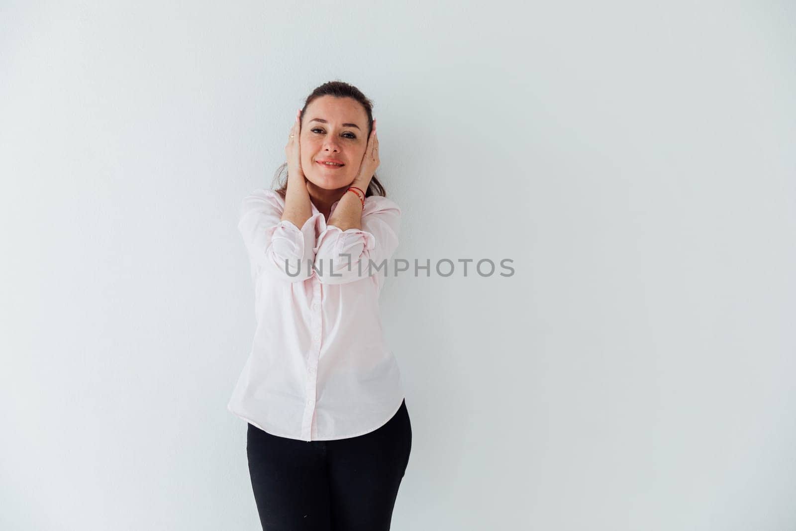 Portrait of a woman of 40 years old in a business suit near a white wall