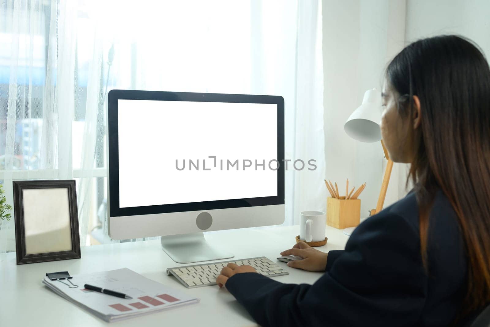 Side view of young businesswoman working on the computer at workplace with natural daylight.