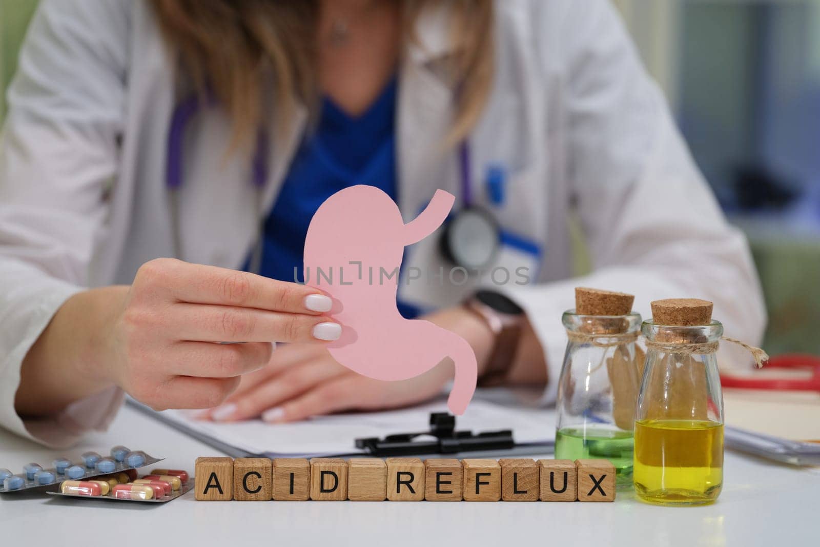 A medical professional is speaking about acid reflux while using a detailed stomach model to explain treatments