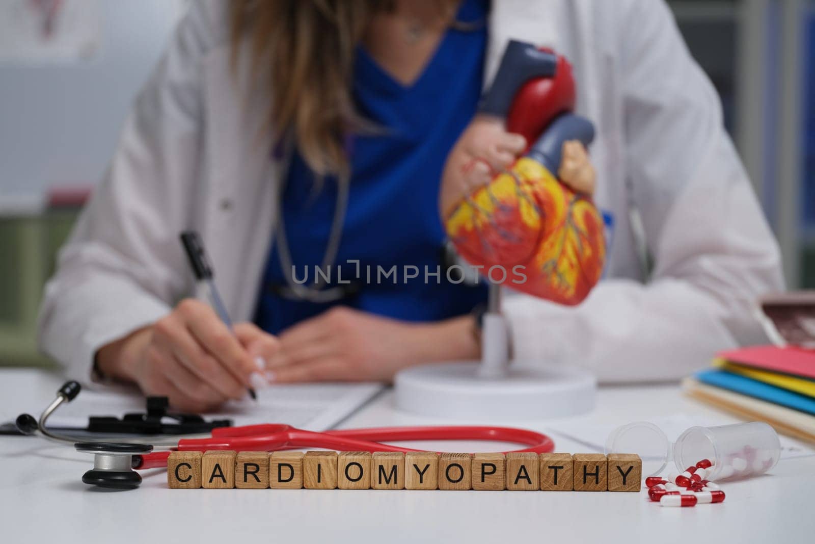 A dedicated medical professional intently studies cardiomyopathy using a detailed heart model and notes