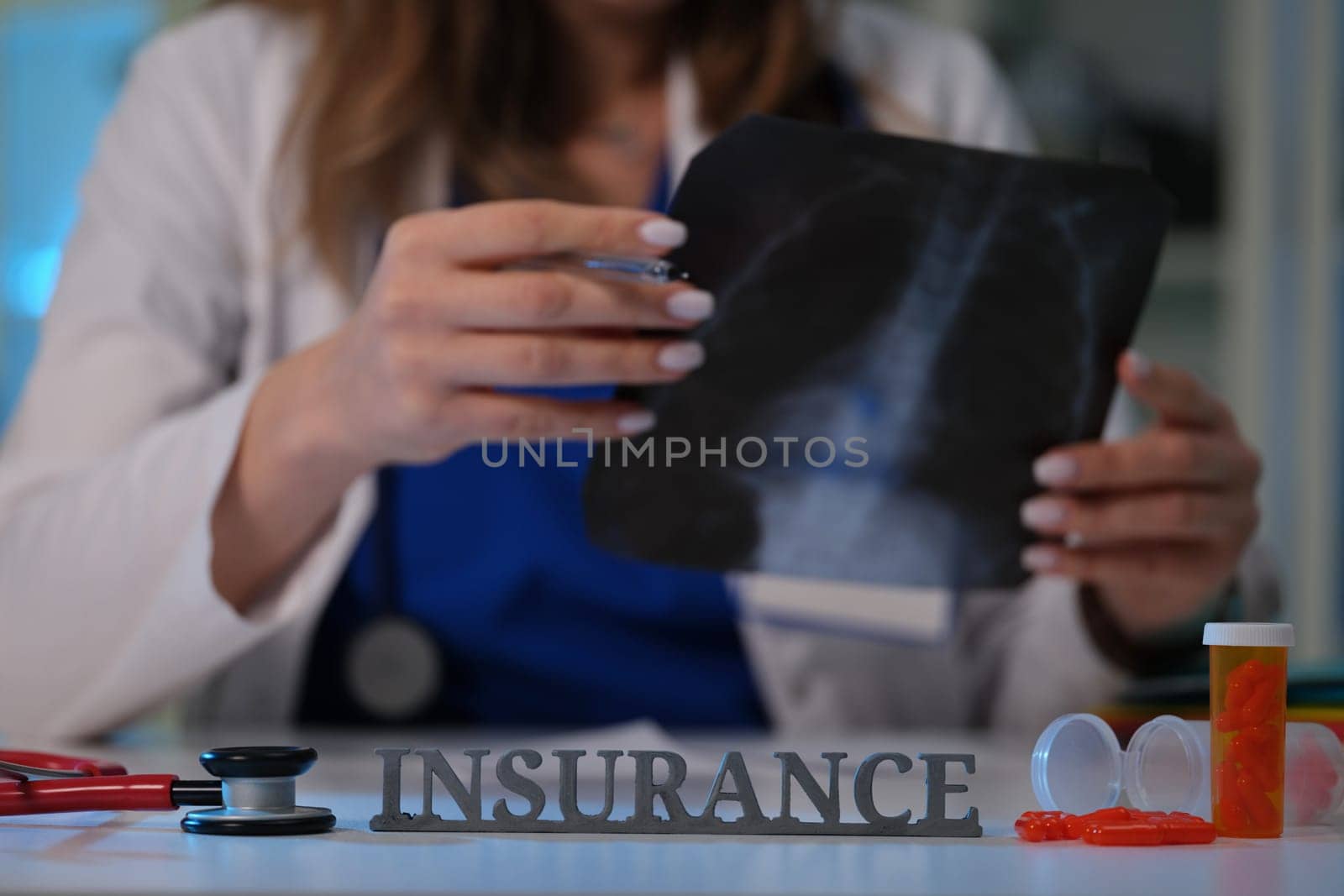 A healthcare professional carefully examines an Xray while discussing the implications of insurance coverage