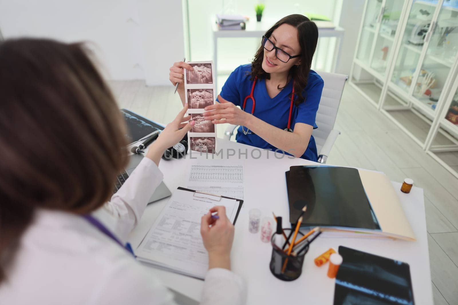 A medical professional carefully reviews diagnostic images with a colleague in a detailed clinical setting
