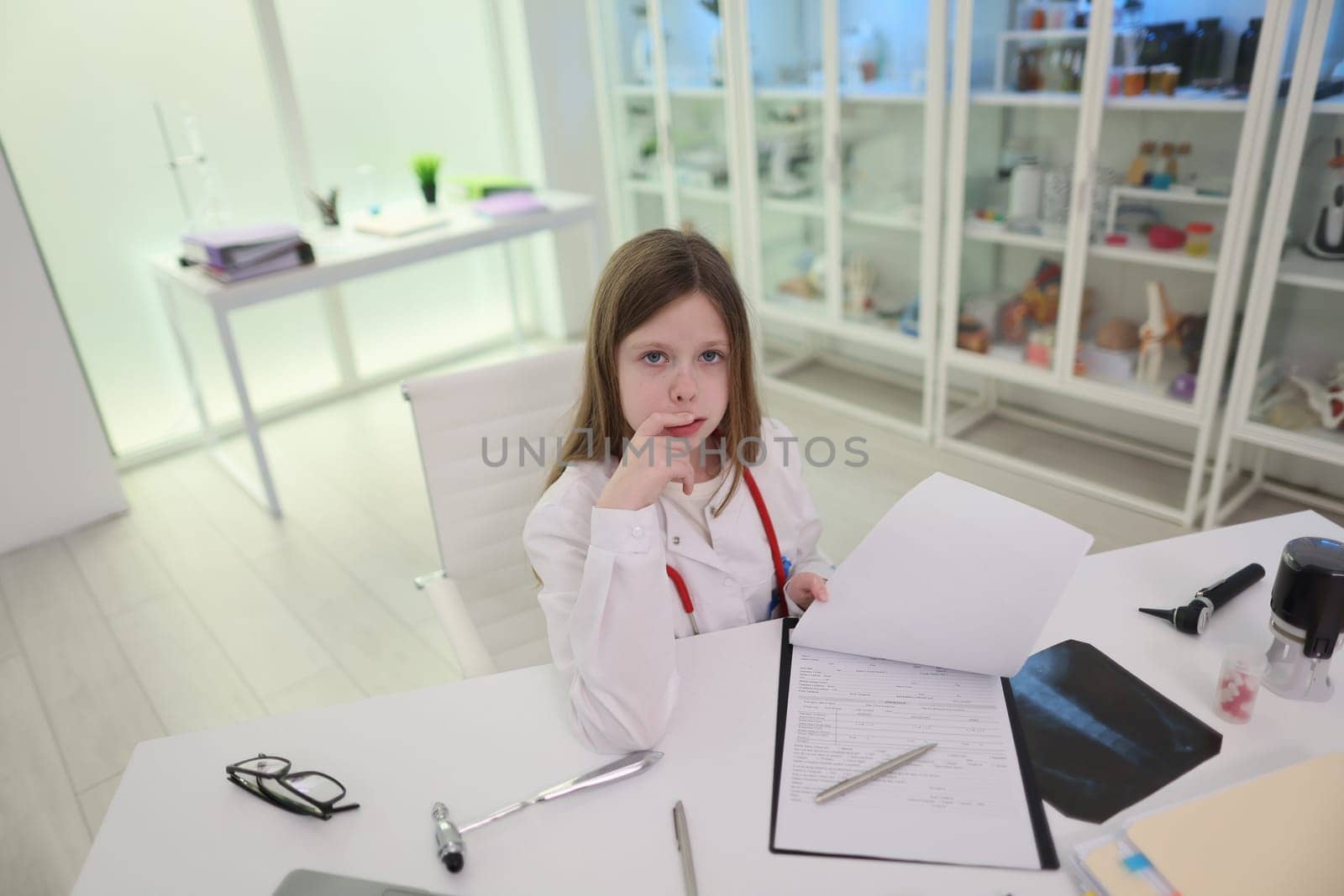 A thoughtful young girl is seated in a bright and contemporary office space, meticulously reviewing various documents