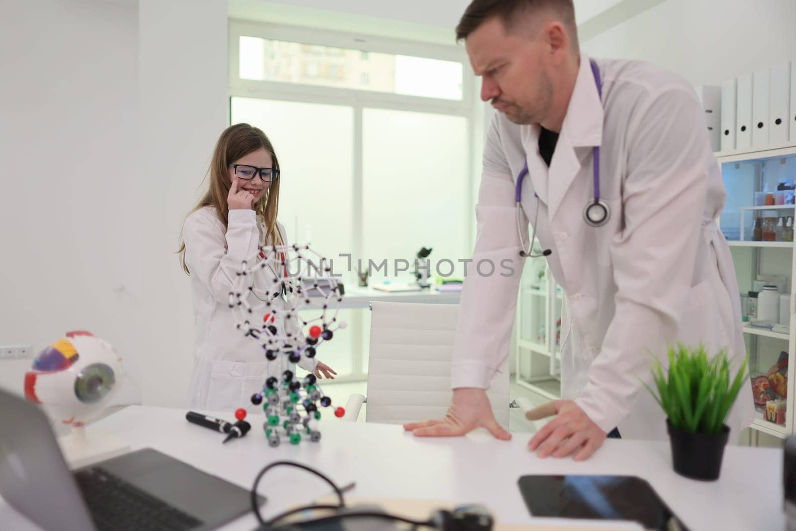 Two skilled healthcare experts are closely examining intricate molecular models within a modern laboratory environment