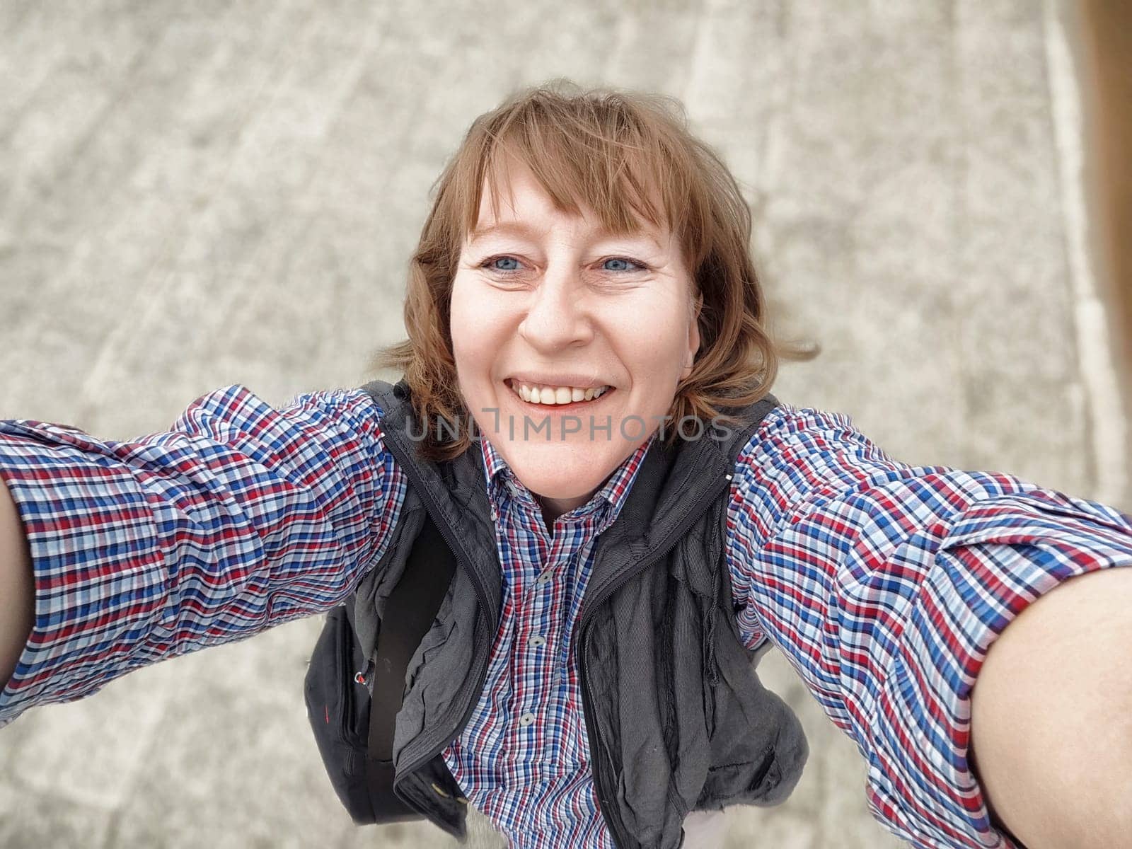 Traveler blogger smiles brightly while taking a selfie, enjoying a perfect day outdoors on her excursion.