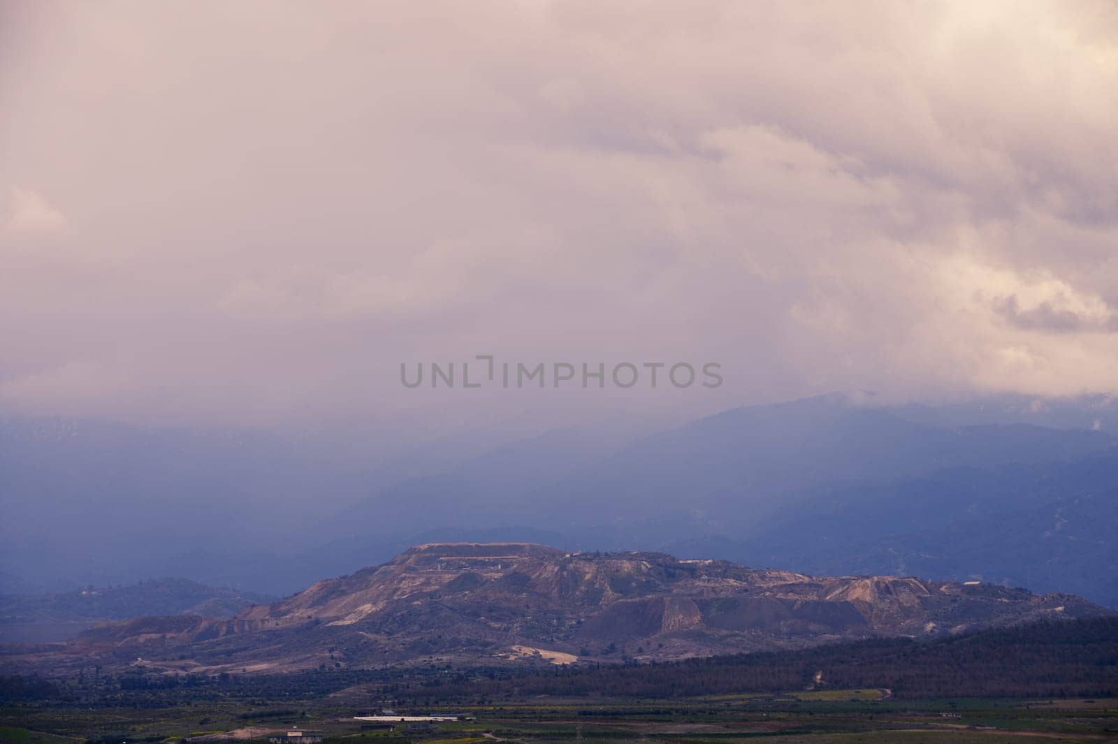 Layers of towering mountains blend seamlessly with rolling mists as dusk approaches, creating a serene atmosphere.