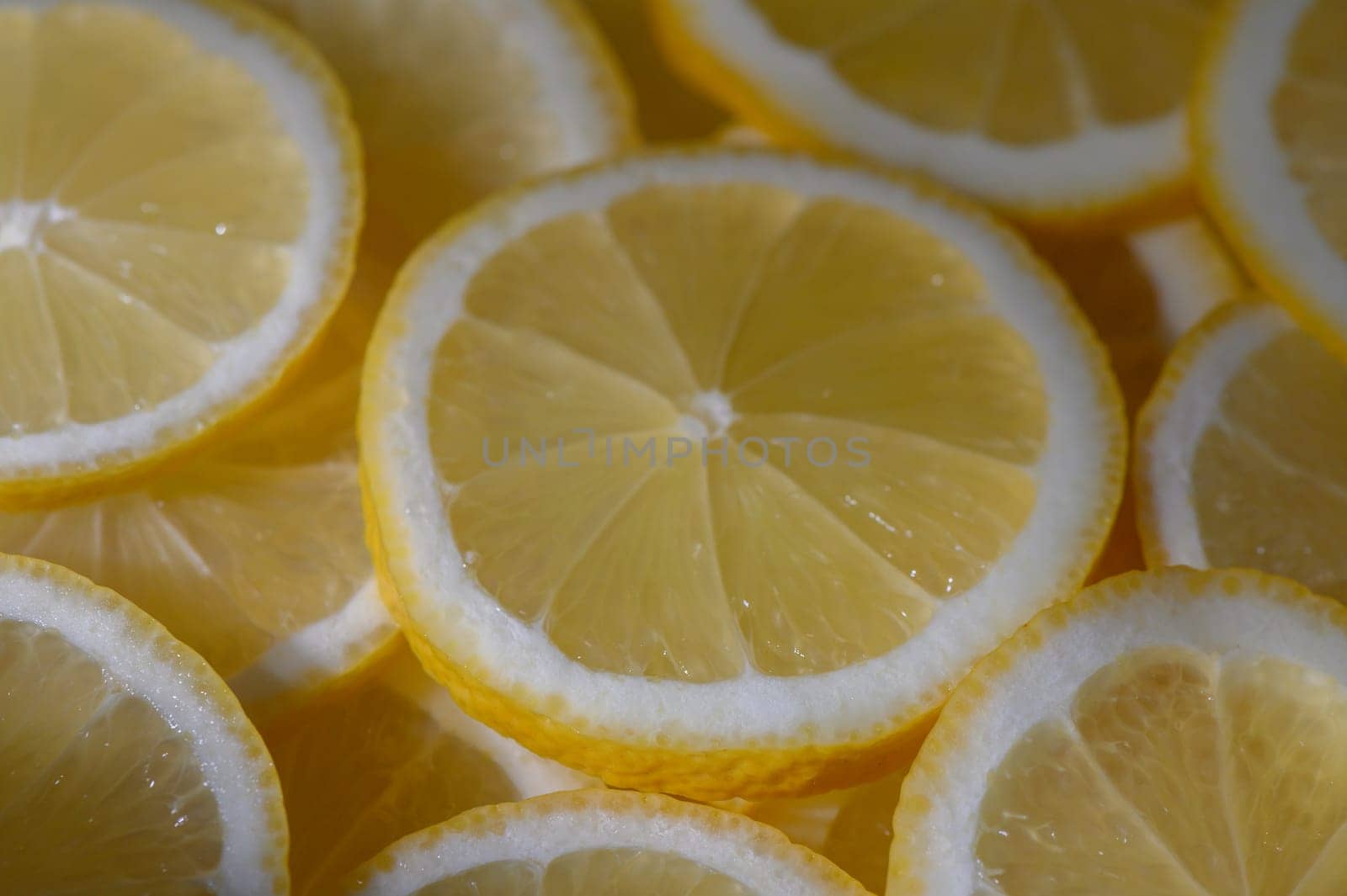 Bright yellow lemon slices rest together, showcasing their juicy texture and inviting aroma in warm light.
