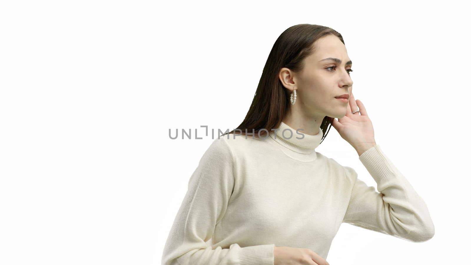 A woman, close-up, on a white background, listens.