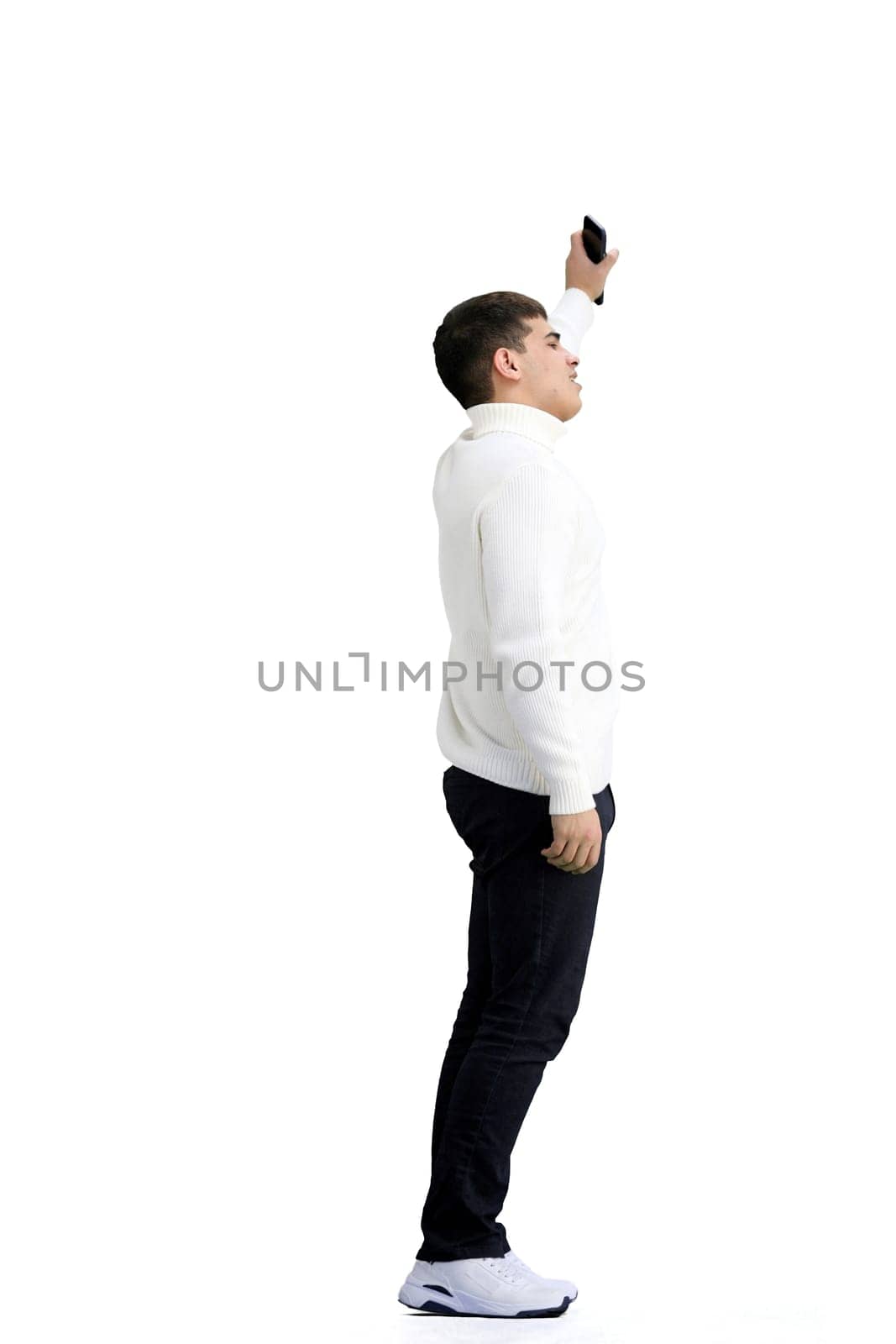 A man, full-length, on a white background, waving his phone.