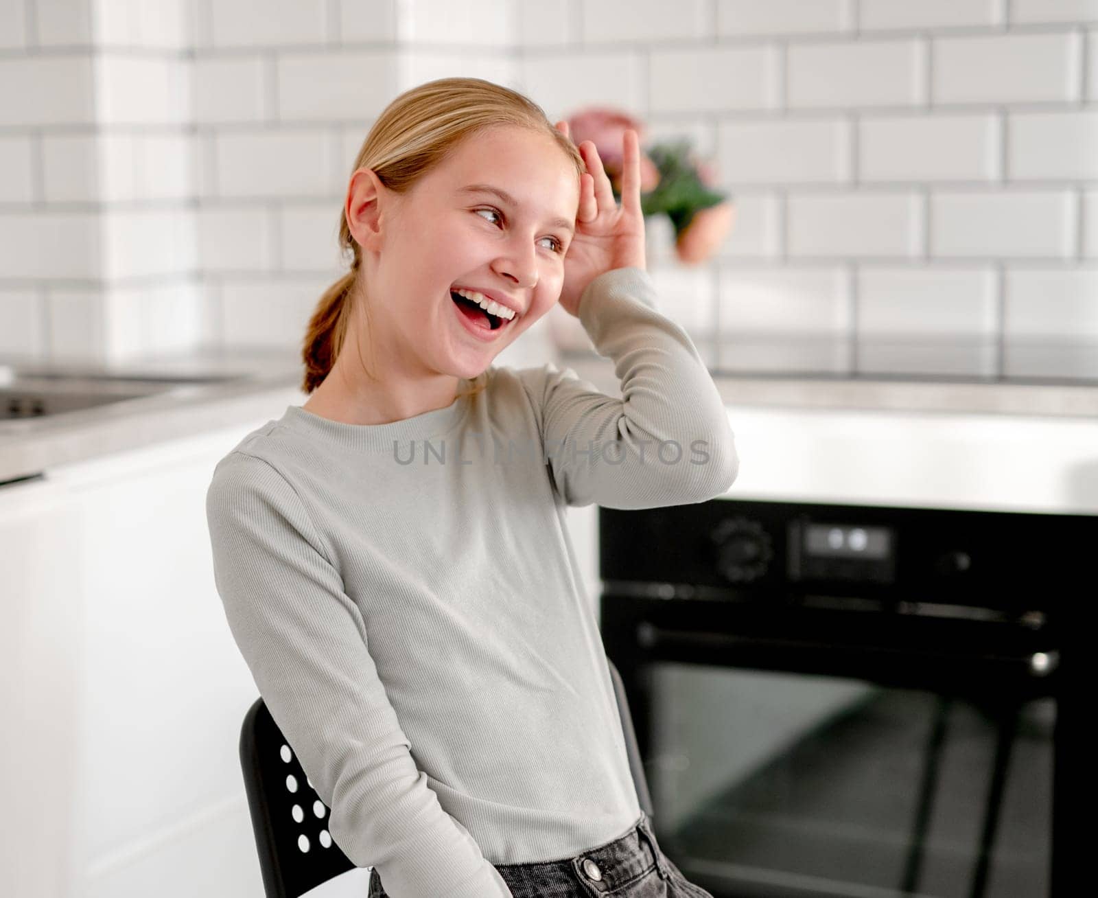 Cute Little Girl Sitting In The Kitchen At Home And Playing Happily