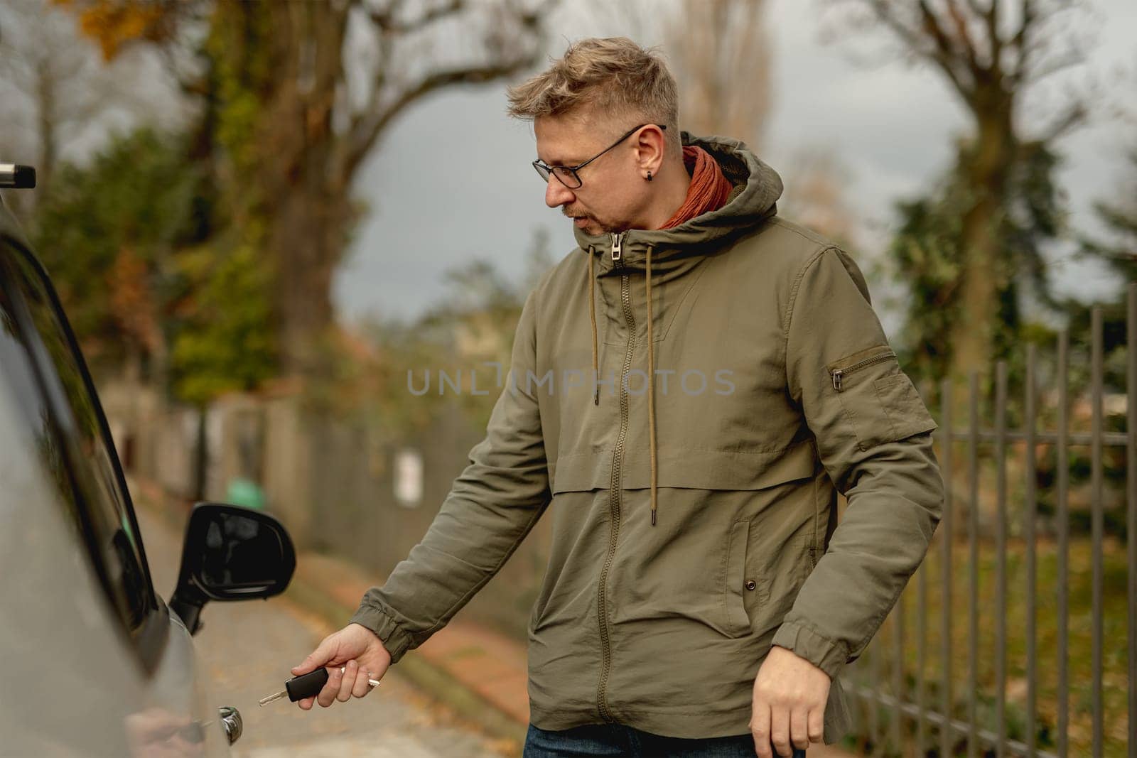 Young Attractive Man Stands On The Street With A Car, Opening The Car Door With A Key