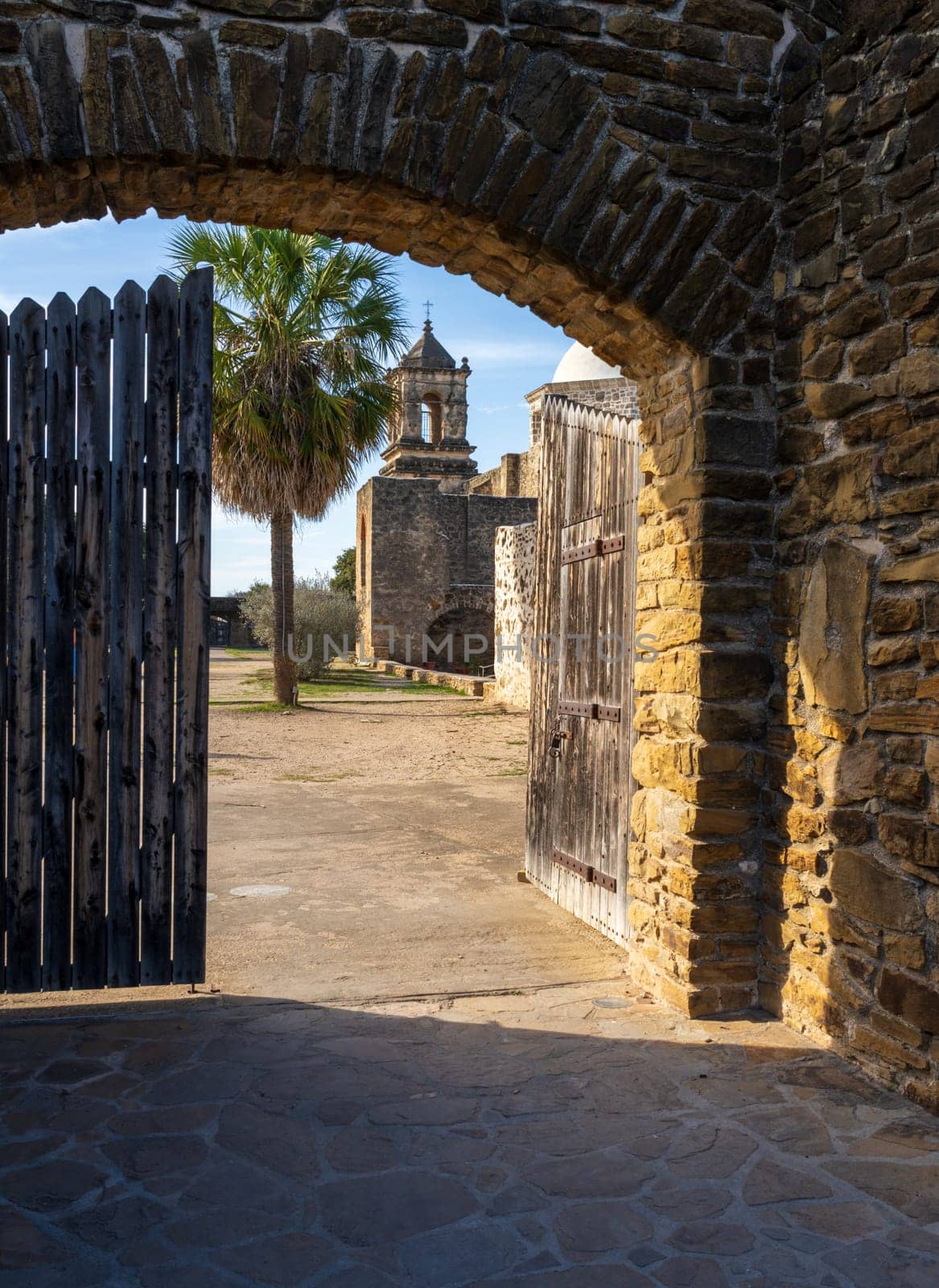 Mission San Jose near San Antonio with church seen through the stone entrance archway and wooden gate