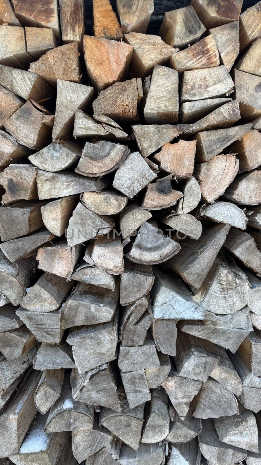 Stack of Natural Firewood Logs Arranged in Rustic Outdoor Setting. Neatly stacked firewood pieces showcasing textures of natural wood grains, ideal for rustic or seasonal themes. Captures the essence of outdoors and sustainable energy sources.