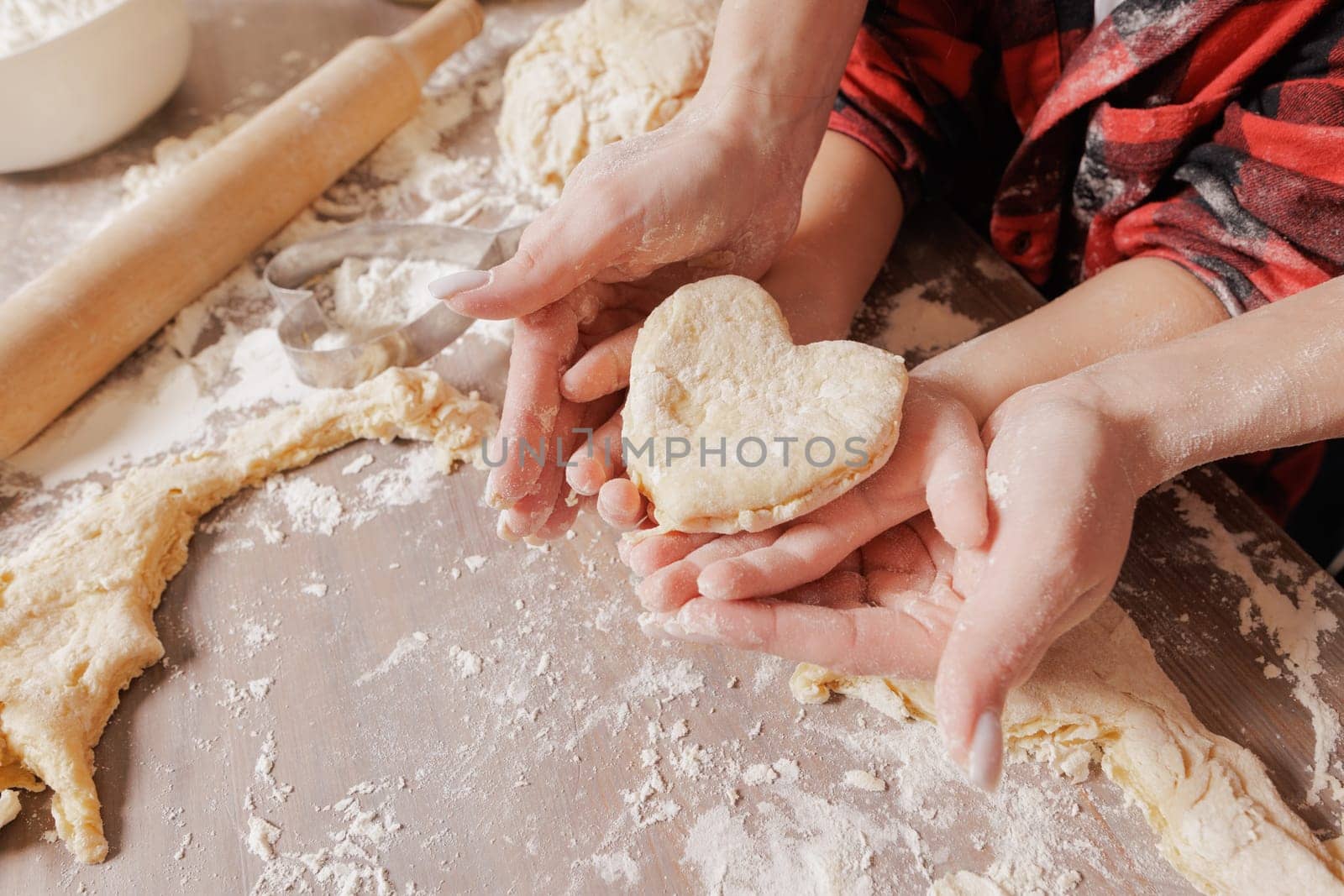 Mother and child baking together, hands holding heart-shaped dough, family bonding, homemade pastry, cozy kitchen scene, flour-covered hands.