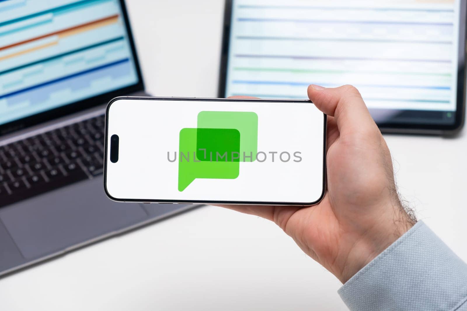 PRAGUE, CZECH REPUBLIC - JANUARY 21 2025: Google chat logo on the screen of a cell phone in business mans hand and laptop on the background.