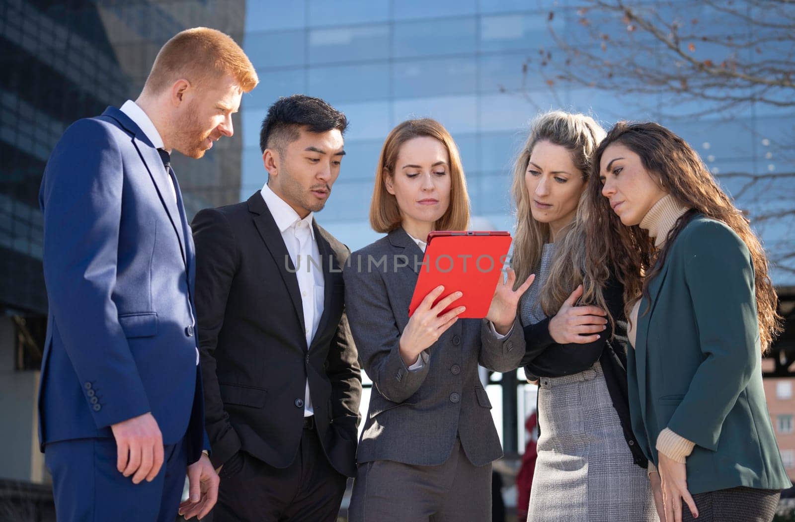 Businesspeople working together using a tablet outside of their office building