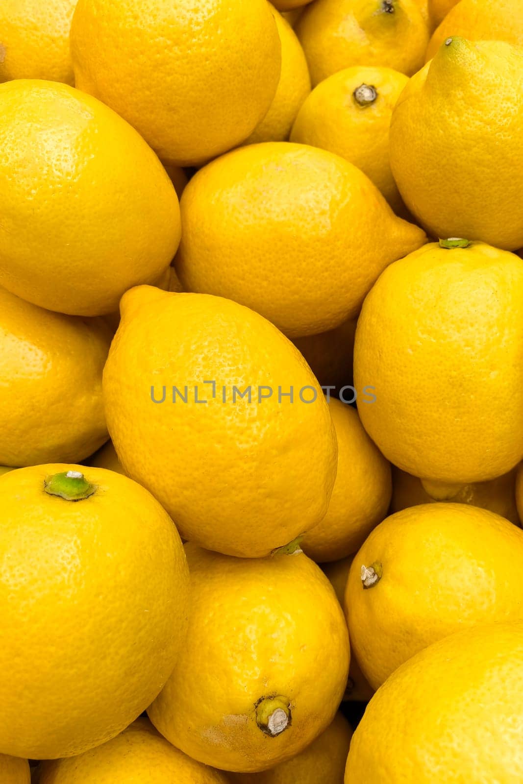 A close-up of juicy bright yellow lemons lying tightly next to each other, creating a visual appeal of shades and textures.