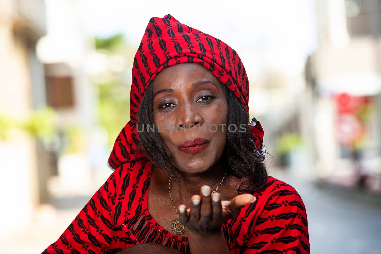 Smiling beautiful young woman in red african outfit makes a flirt on camera. Shopping with love concept