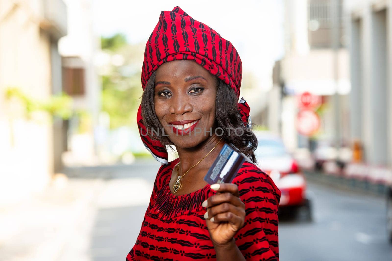 happy woman to go shopping in city, presents a credit card to the camera in sunny day. Sales, consumption and people concept.