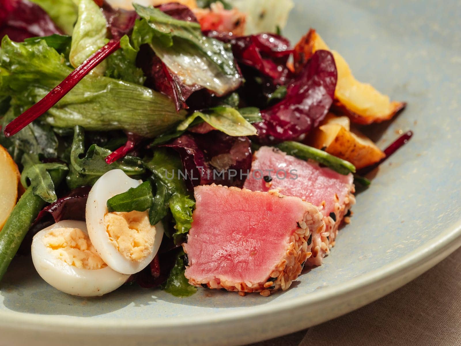 Asian style tuna salad with lettuce, eggs, cherry tomatoes potato and tuna pieces in sesame seeds. Healthy tuna salad. Close up.