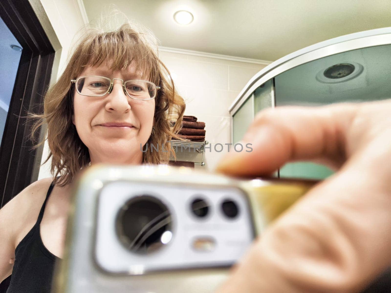Early morning selfie taken by a blonde female blogger in her bathroom, showcasing her casual style and surroundings.