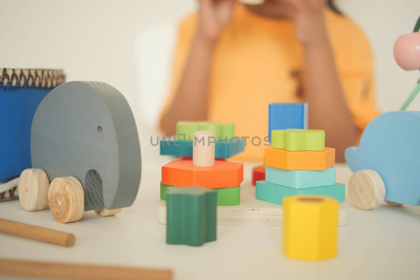 A child engages with various colorful wooden toys and shapes.