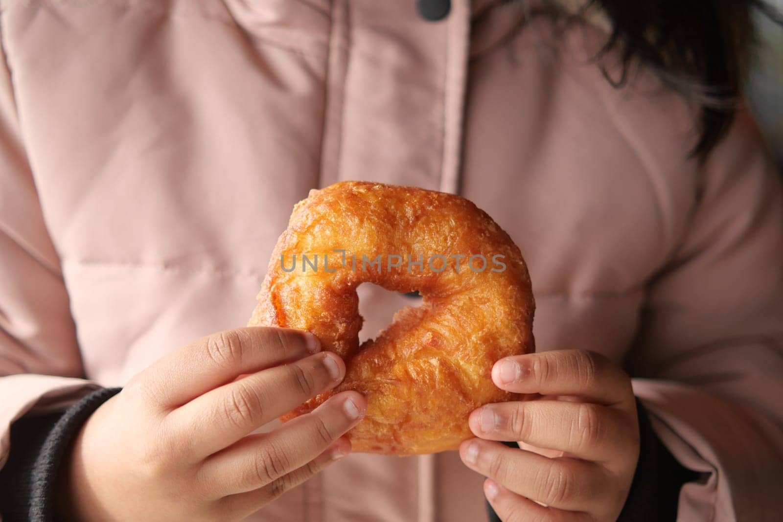 A person enjoys a golden pastry in their hands during chilly weather.