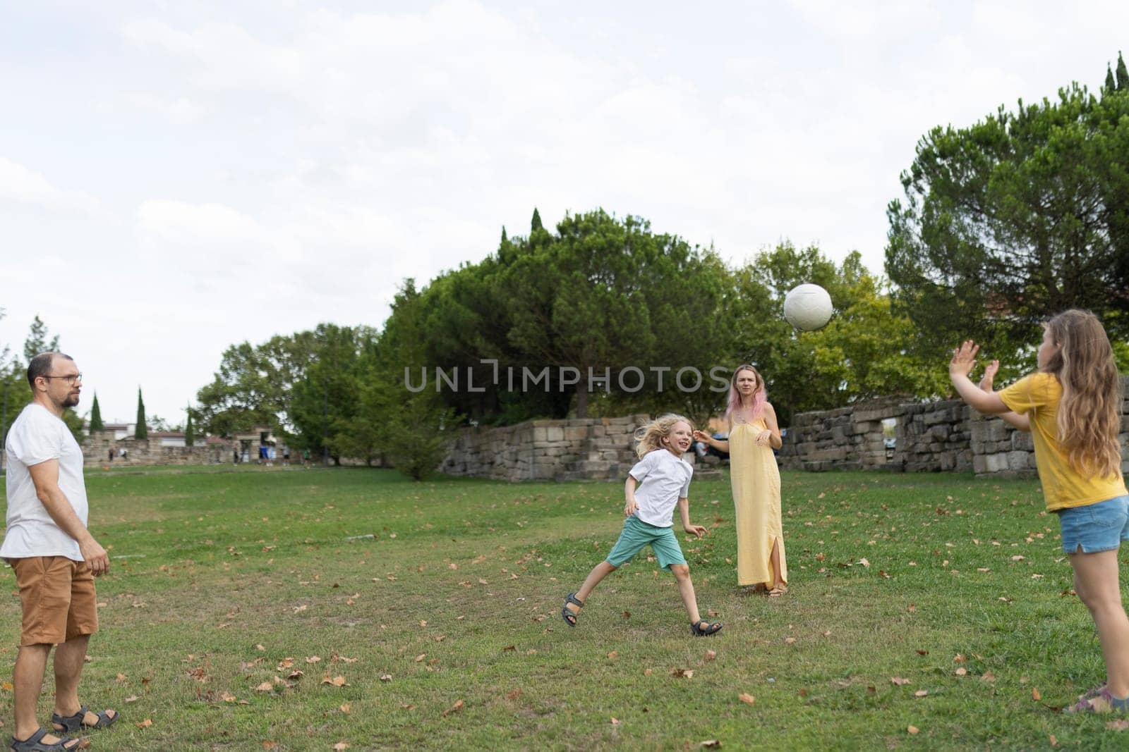 Family enjoying quality time together, playing with ball in park, promoting healthy lifestyle and family bonding