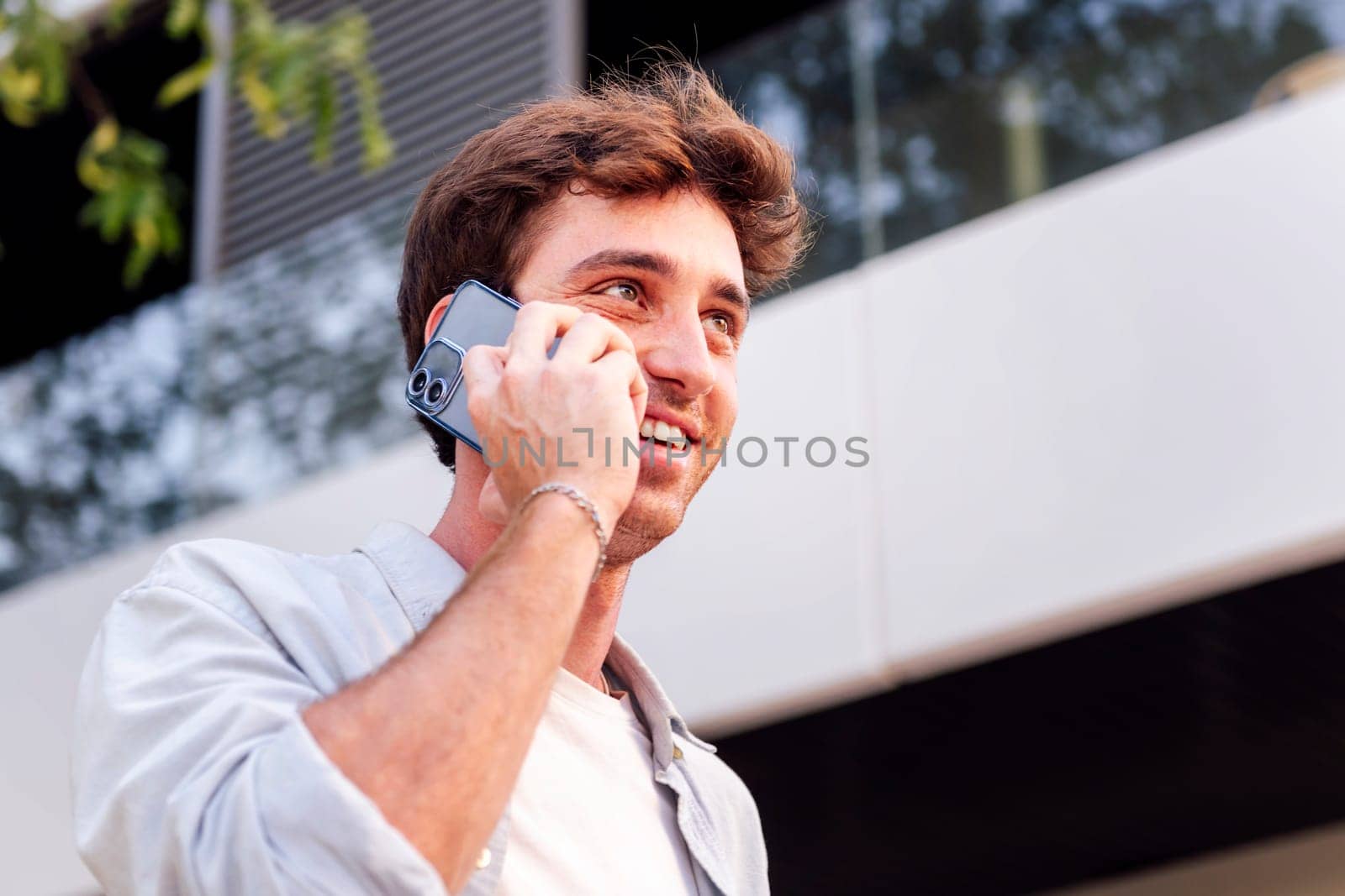 man smiling happy while walking down the street in a good mood talking on cell phone, concept of technology of communication and urban lifestyle, copyspace for text